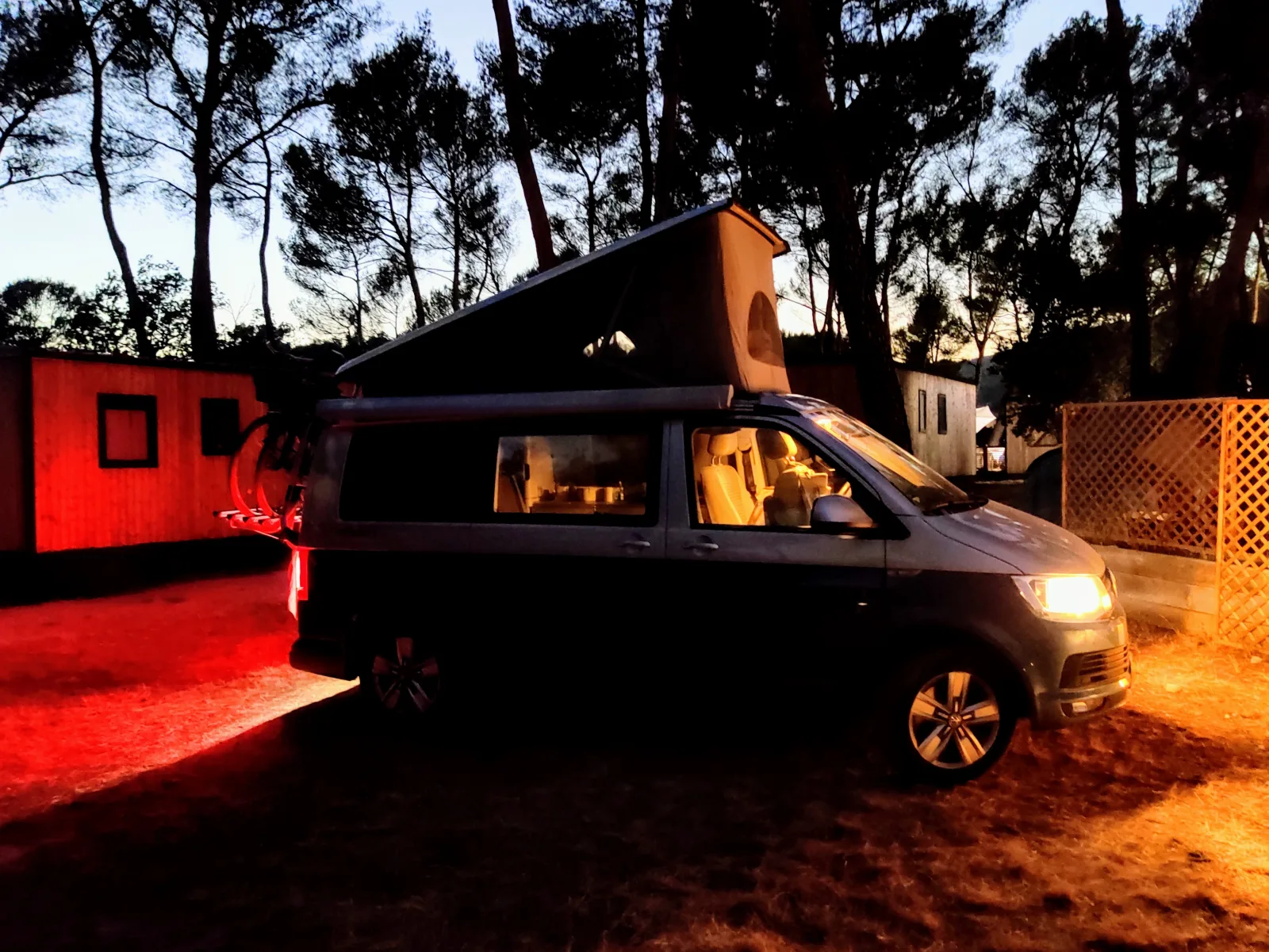 VW California mit geöffnetem Aufstelldach auf einem abendlichen Campingplatz